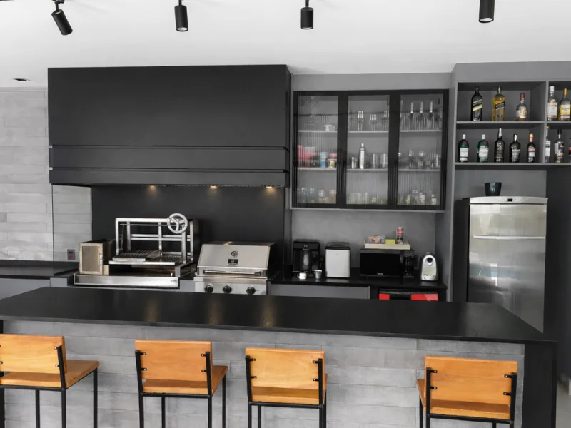 Coifa de embutir preta instalada sobre churrasqueira de inox em ambiente gourmet planejado